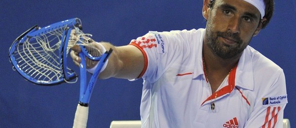 Baghdatis of Cyprus holds up a racquet that he smashed during a break in play against Wawrinka of Switzerland at the Australian Open in Melbourne